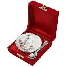 a silver plate in a red velvet box with a spoon and fork on it's side