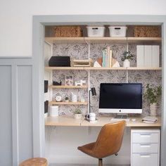 a desk with a computer on top of it and some shelves above the desk in front of it