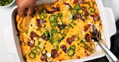 a person grabbing a piece of pizza from a casserole dish with green peppers and onions