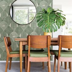 a dining room table with green chairs and a round mirror on the wall above it