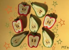 apples and pears cut in half on a yellow surface with stars around them as if they were carved to look like faces