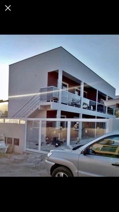 a car is parked in front of a building with stairs on the second floor and two balconies above it