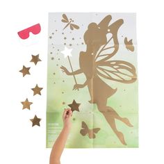 a hand is pointing at the silhouette of a fairy on a sheet of paper with gold stars