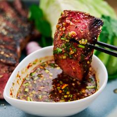 chopsticks sticking out of a bowl filled with meat and sauce next to lettuce