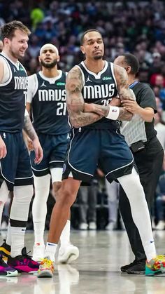 three basketball players standing on the court with their arms crossed and looking at each other