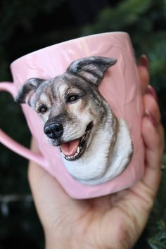 a hand holding a pink coffee mug with a dog on it's side and its mouth open