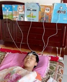 a young boy laying in bed with headphones attached to the wires above his head