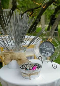 a white table topped with a bowl filled with lots of silver colored pins and needles