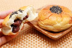 a person holding a pastry in front of a bun on a wooden plate with sprinkles