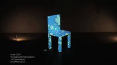 a blue chair sitting on top of a black floor next to a light up wall