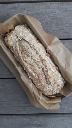 a loaf of bread sitting in a paper bag on top of a wooden table next to a knife