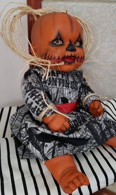 a creepy doll sitting on top of a striped pillow