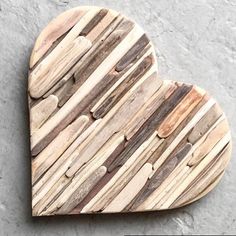 a heart shaped wooden object made out of wood planks on a gray surface with white and brown stripes