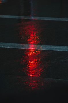 a red light reflecting off the wet pavement