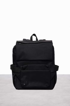 a black backpack sitting on top of a cement floor next to a white wall,