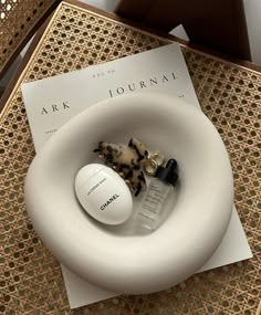 a white object sitting on top of a table next to a magazine and bottle of perfume