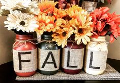 three jars with flowers in them sitting on a table