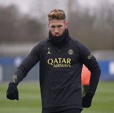 a man in black jacket and gloves on soccer field