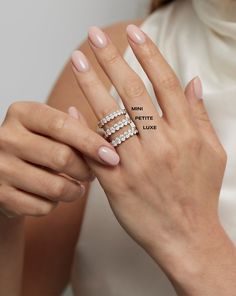 a woman's hand holding a ring with three rows of diamonds on the middle