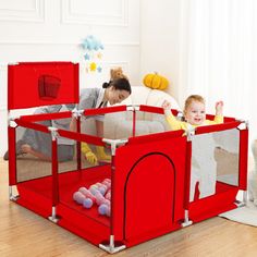 a woman and child playing in a red playpen