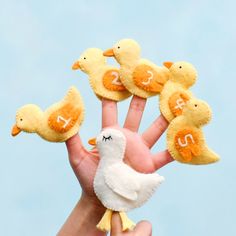 a hand holding five little yellow ducks with the letter f on it's fingers