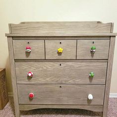 a wooden dresser with several knobs on the top and bottom drawers, in front of a wall