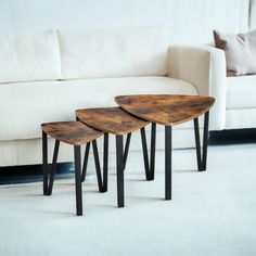 three wooden tables sitting on top of a white carpeted floor next to a couch