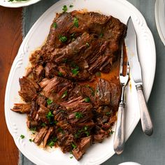 a white plate topped with meat covered in sauce and garnished with parsley