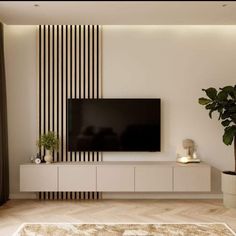 a flat screen tv sitting on top of a white entertainment center next to a potted plant