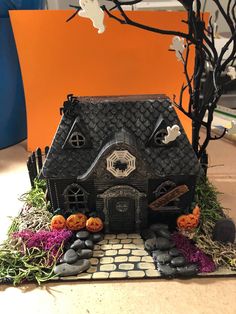 a halloween house made out of fake rocks and grass with pumpkins on the ground