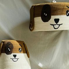 two brown and white purses with faces on them, one has a dog's face painted on it