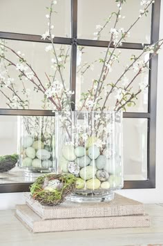 two vases filled with flowers and eggs sitting on top of a table next to a mirror