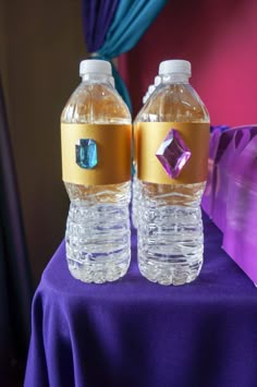 two water bottles sitting on top of a purple table cloth