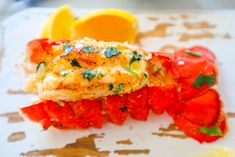 lobster on a plate with lemon wedges and garnished with parmesan cheese