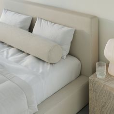 a bed with white sheets and pillows next to a night stand on a nightstand table