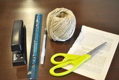 a pair of scissors, yarn, and tape are on a table next to a ball of string