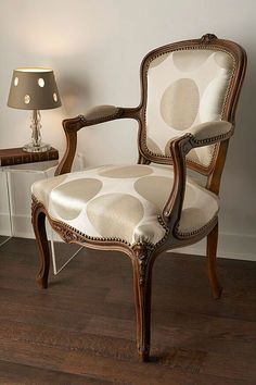 a chair sitting on top of a hard wood floor next to a table with a lamp