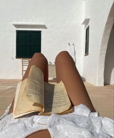 a person laying on the ground reading a book with their legs crossed and feet propped up