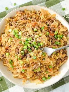 a bowl filled with noodles and meat on top of a green checkered table cloth