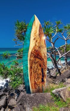 a surfboard sitting on top of a rock near the ocean