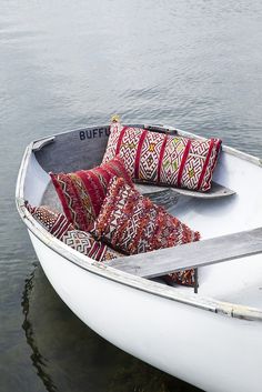 a small white boat with decorative pillows in the water