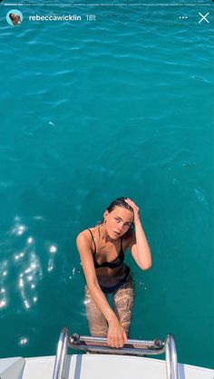 a woman standing in the water on top of a boat with her hand near her head