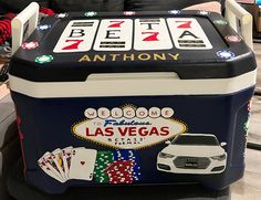 a las vegas themed cooler sitting on top of a chair with cards and dice around it