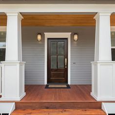 the front porch of a house with white pillars and wooden steps leading up to it