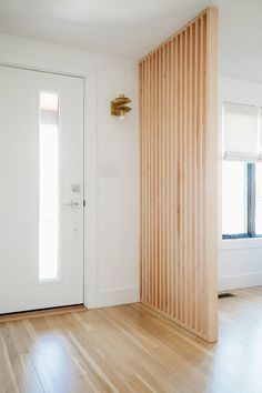 an empty room with wooden slats on the wall and white door in the corner