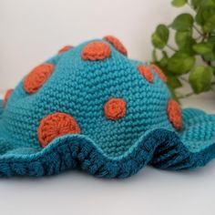 a crocheted blue hat with orange dots on it