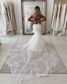 a woman standing in front of a mirror wearing a wedding dress with an open back