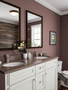 a bathroom with two sinks and a mirror above the sink, along with a toilet