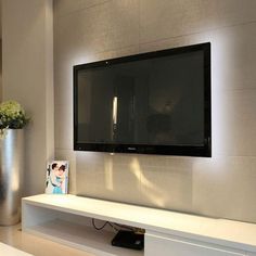 a flat screen tv mounted to the side of a wall next to a vase with flowers