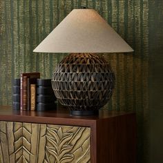 a lamp sitting on top of a wooden table next to a book shelf with books